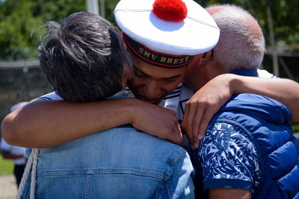 Un jeune matelot retrouve ses parents après être partit en mission. Il enlace ses deux parents.