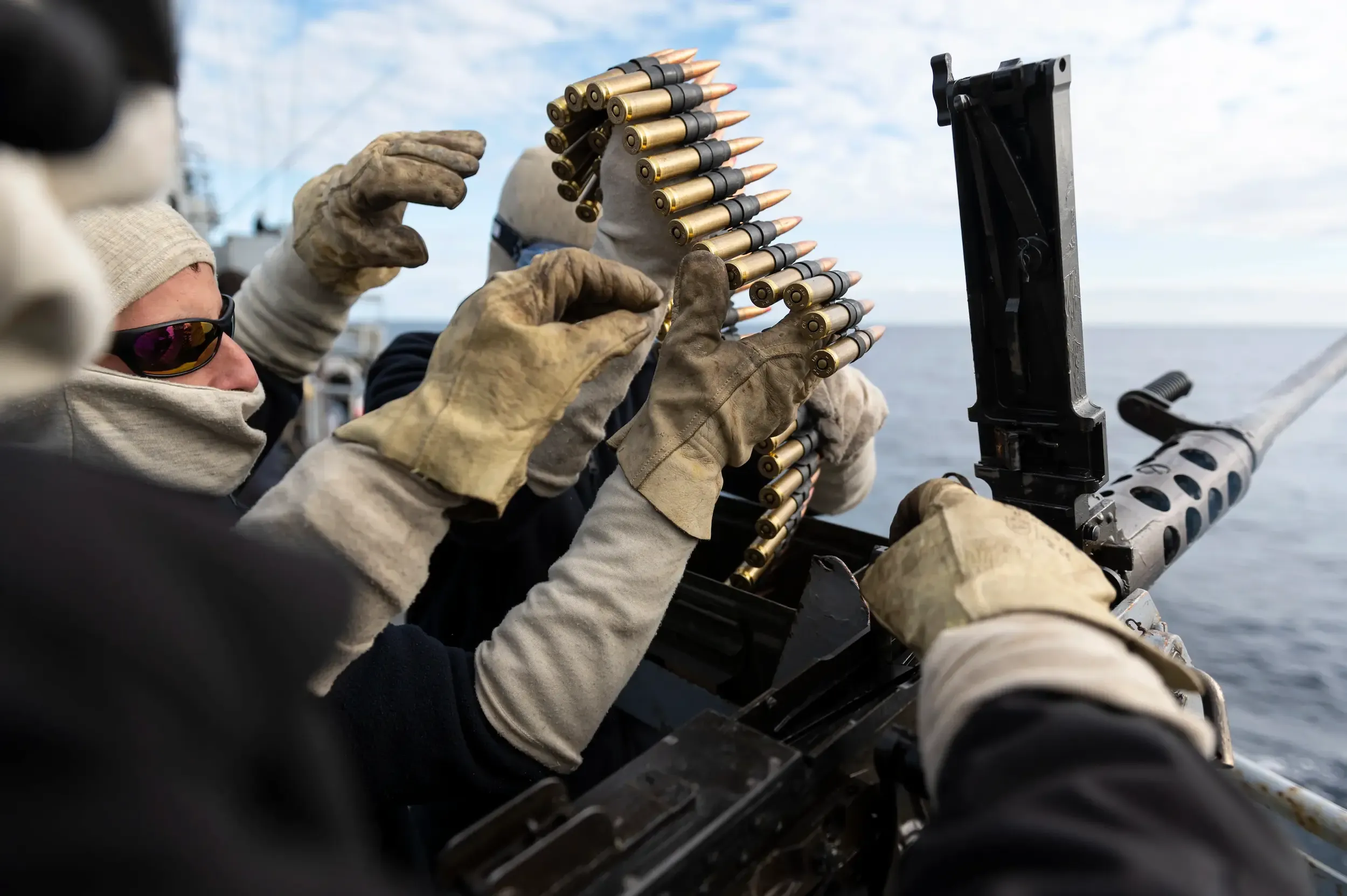 Un technicien d'armes et munitions en train de recharger une mitrailleuse sur un bateau de la marine nationale.