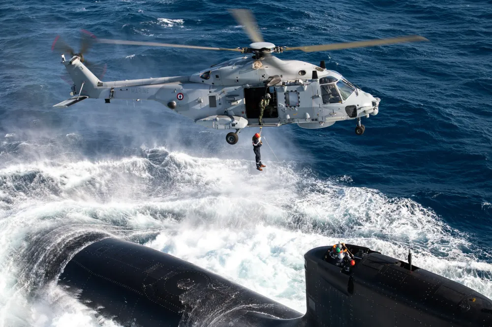 Hélicoptère NH90 en intervention au-dessus d'un sous-marin à la surface de la mer 
