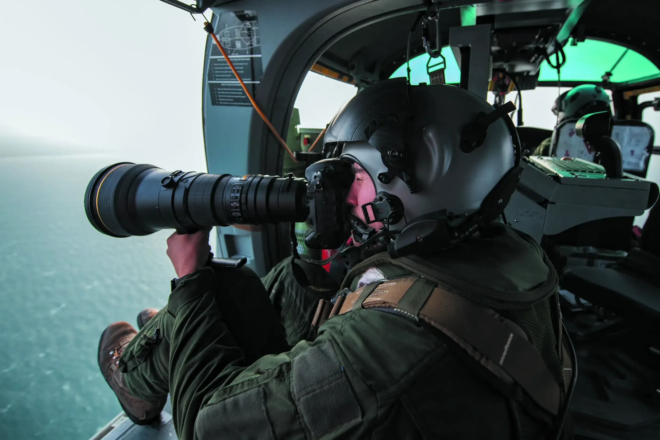 Un analyste du renseignement en spécialité image en train de prendre des photos depuis un hélicoptère.