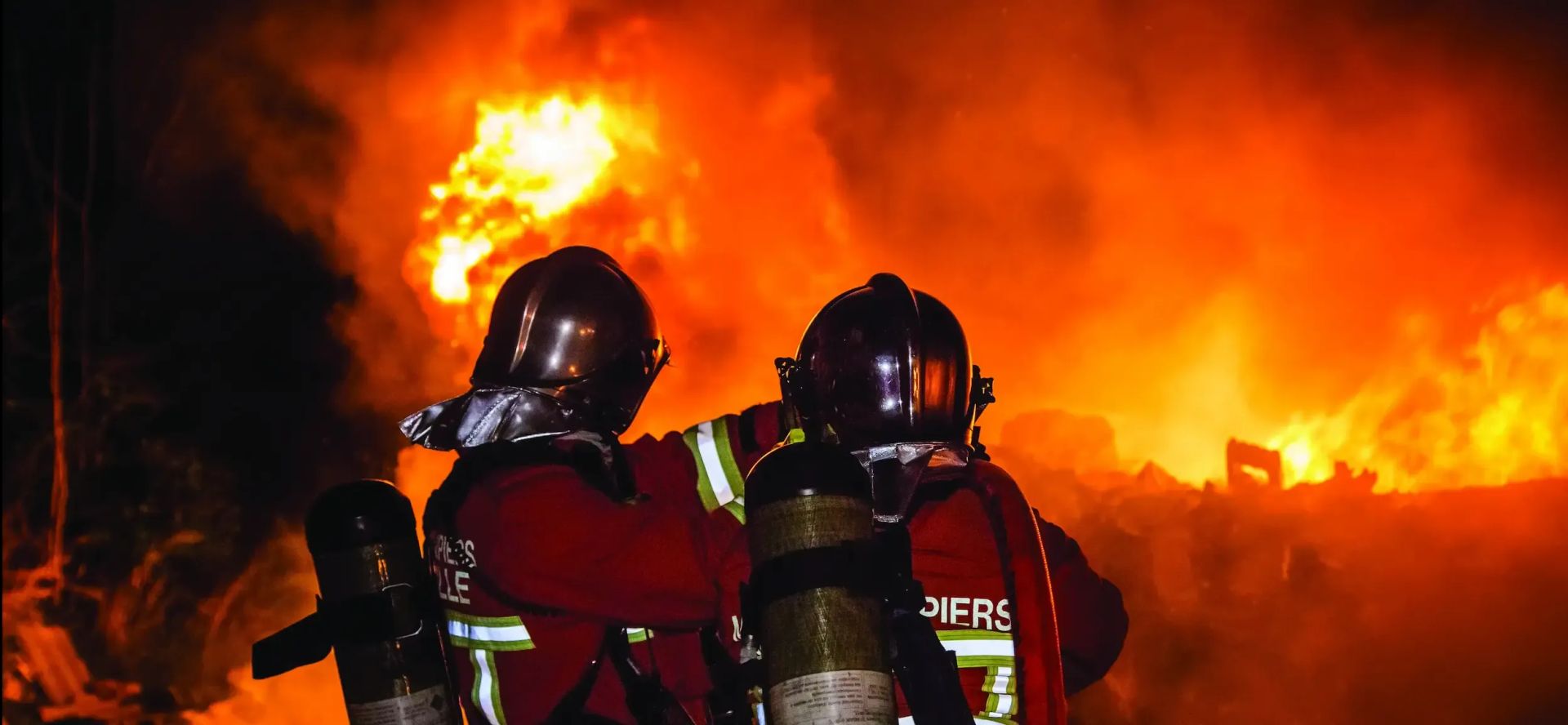 Des marins pompiers en train de combattre un incendie ravageur avec de grandes flammes.