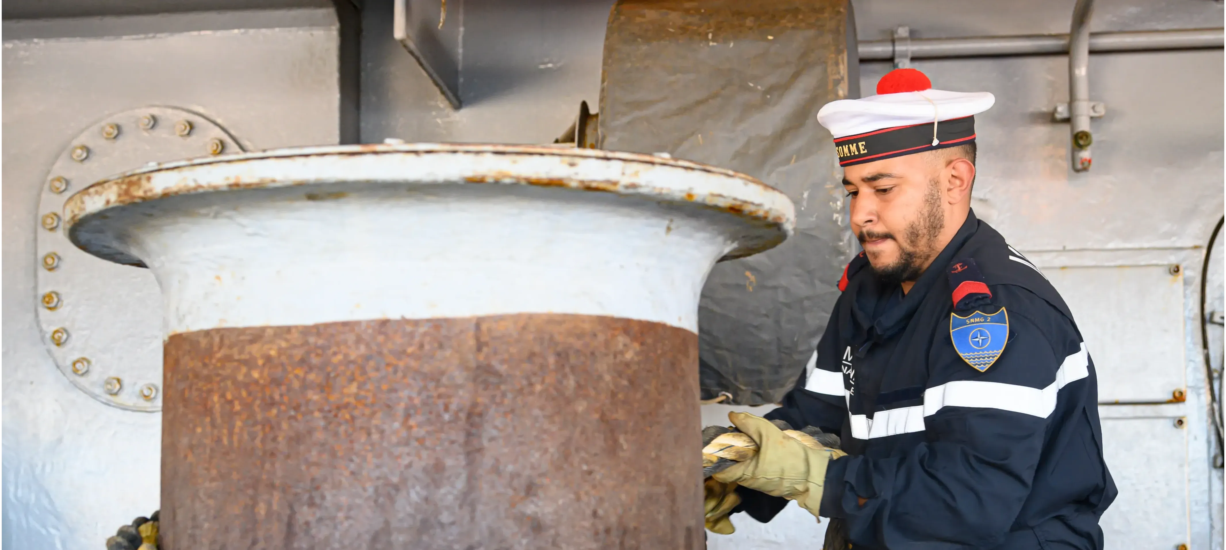 Un matelot en uniforme en train d'enrouler une corde