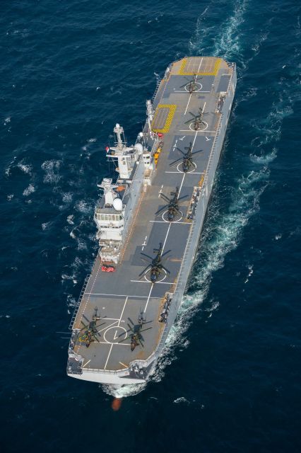 une porte helicoptere amphibien ou PHA en train de naviguer avec plusieurs hélicoptères postés dessus