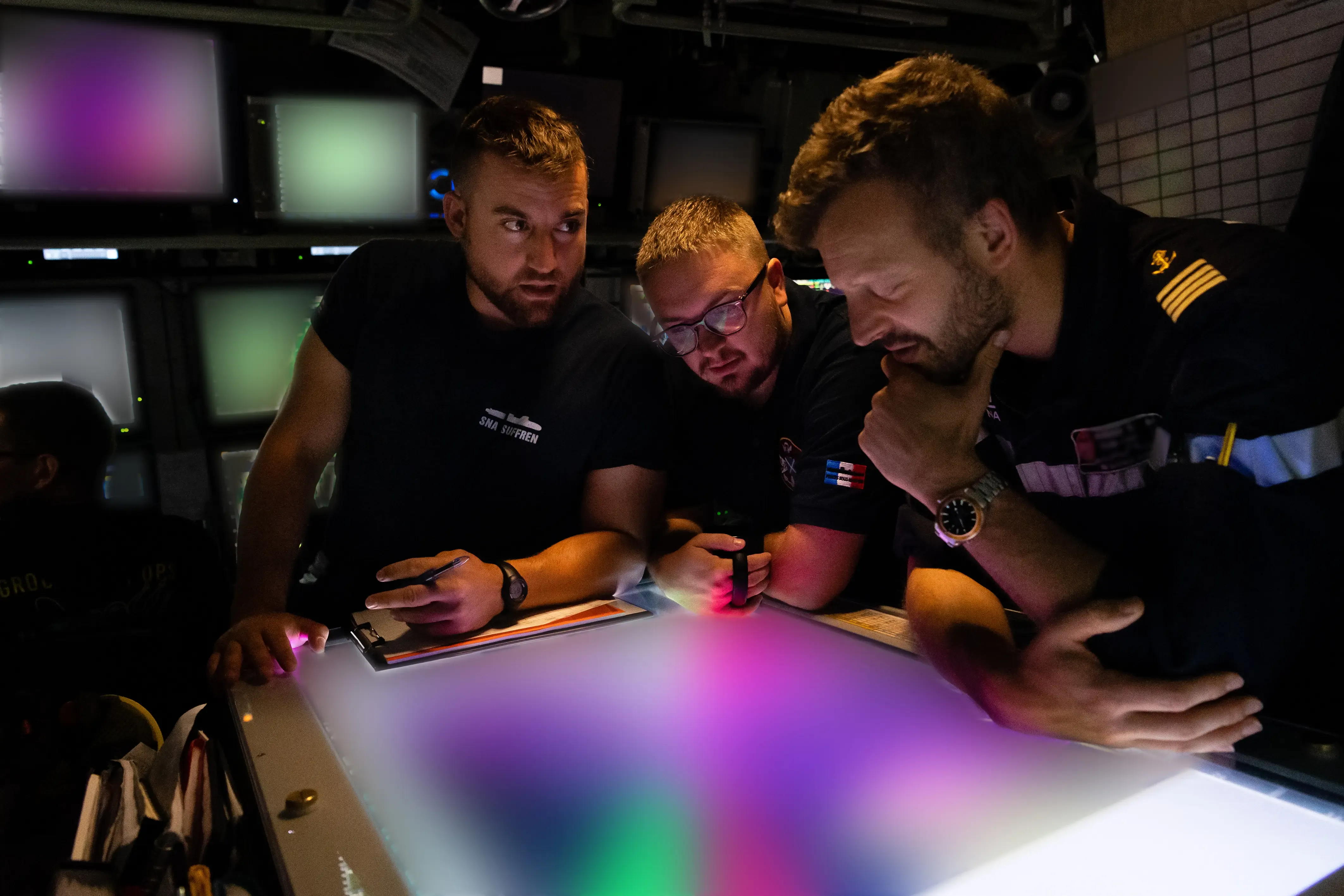 Une équipe de marins détecteurs anti sous-marins en train d'analyser des écrans de données flouées car secret défense 