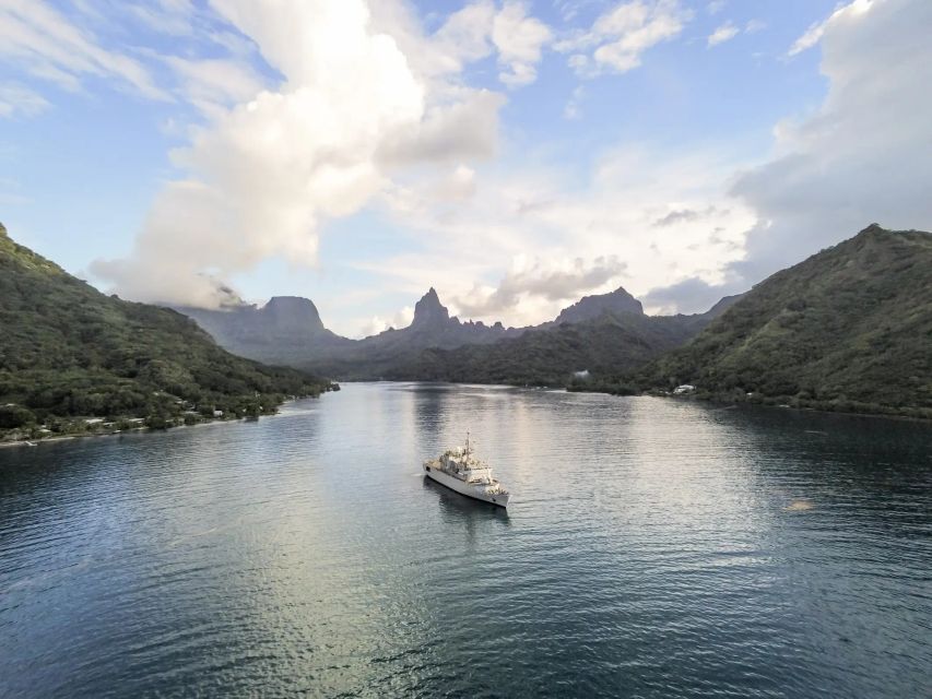 Un navire de la marine nationale au milieu d'une baie paradisiaque, entourée de collines boisées.