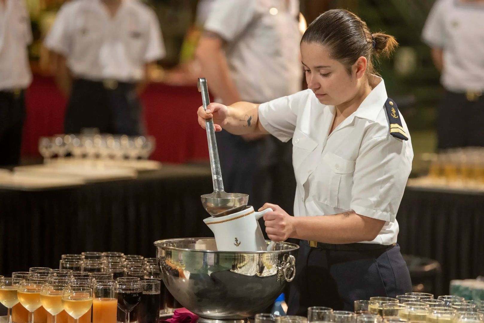 Un second-maître de spécialité restauration en train de servir des cocktails lors d'une réception.