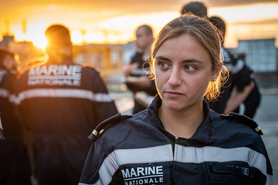 Une lieutenant de la force sous-marine en tenue de service courant avec son groupe de collègue.
