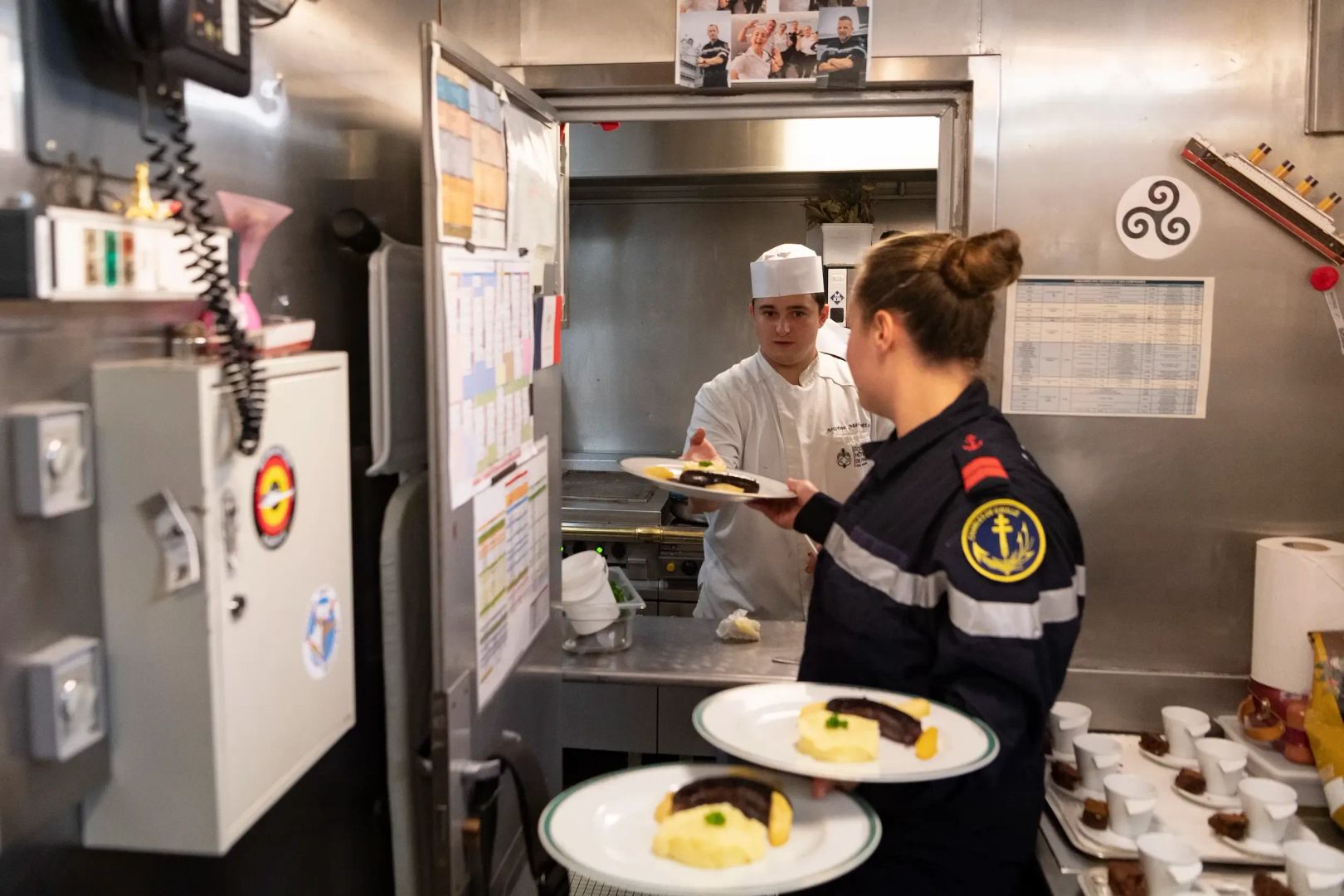 Un matelot de spécialité restauration en train de récupérer les plats en cuisine.