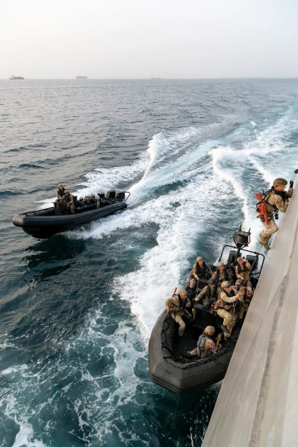 Deux zodiacs de la marine en train d'aborder un bateau pirate en pleine mer.