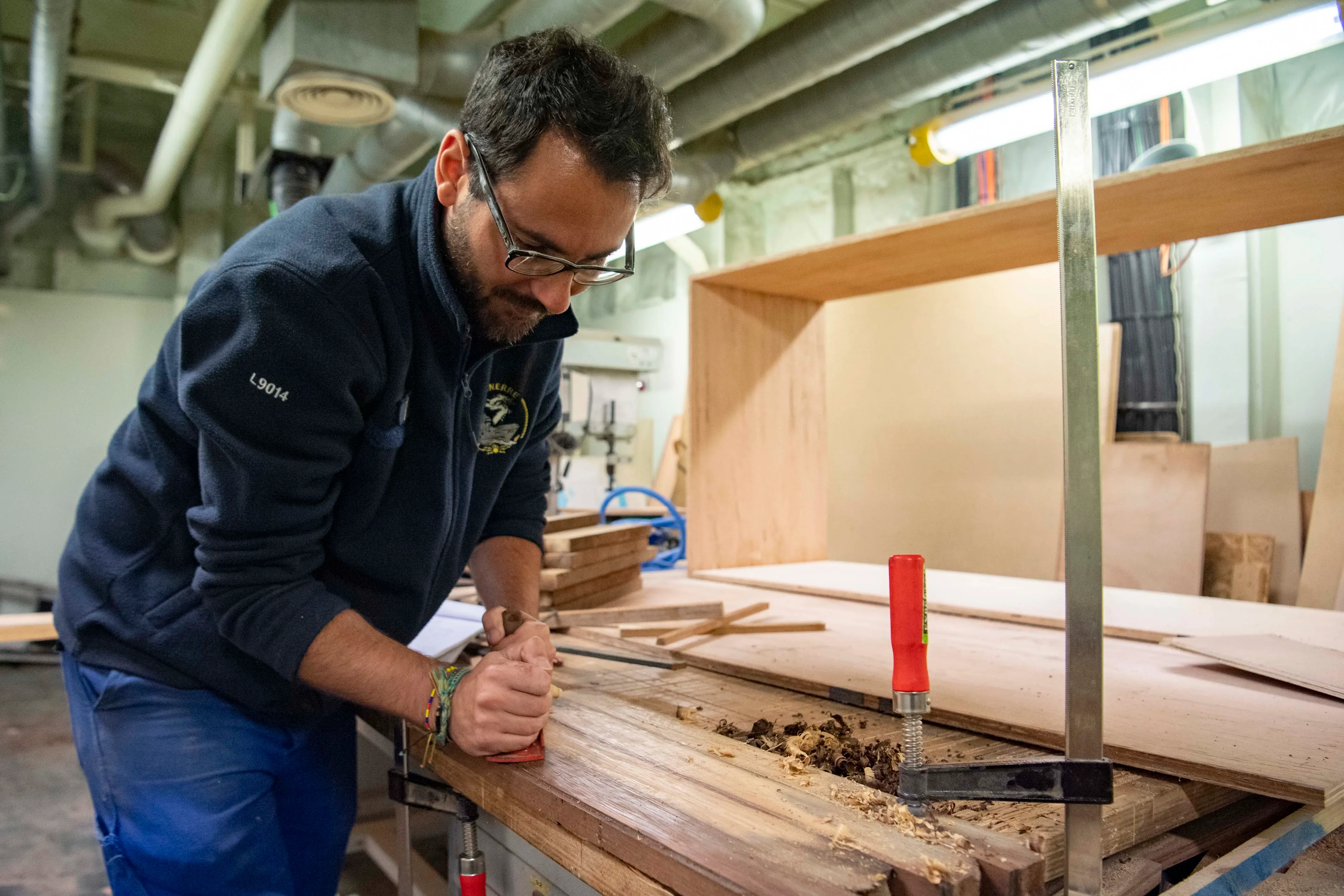 Marin charpentier en train de travailler du bois dans un atelier naval de la marine nationale