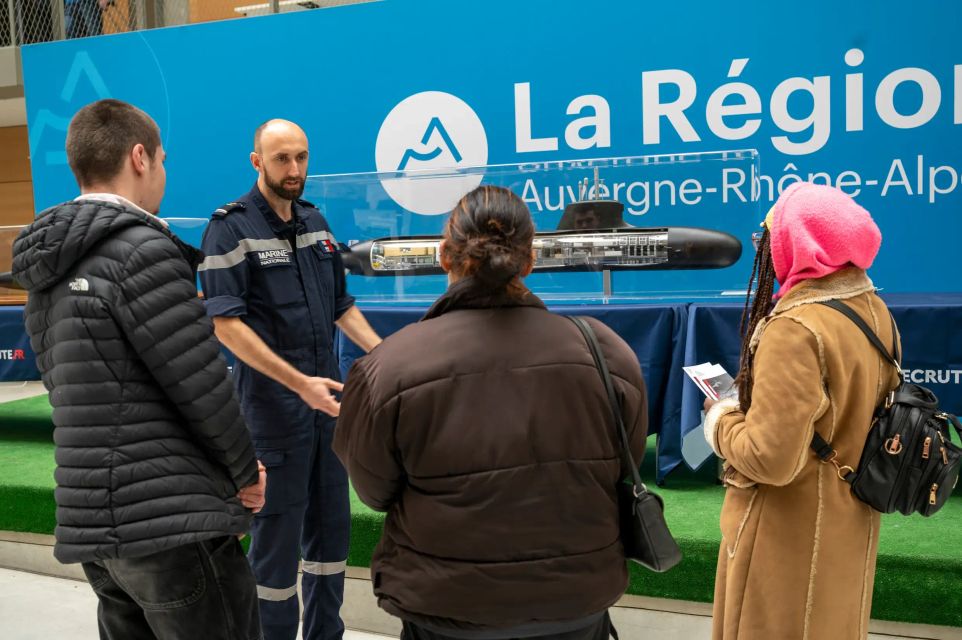 Un marin conseiller sur un stand sous-marin lors d'un évènement de recrutement à Lyon, en train de discuter avec trois jeunes