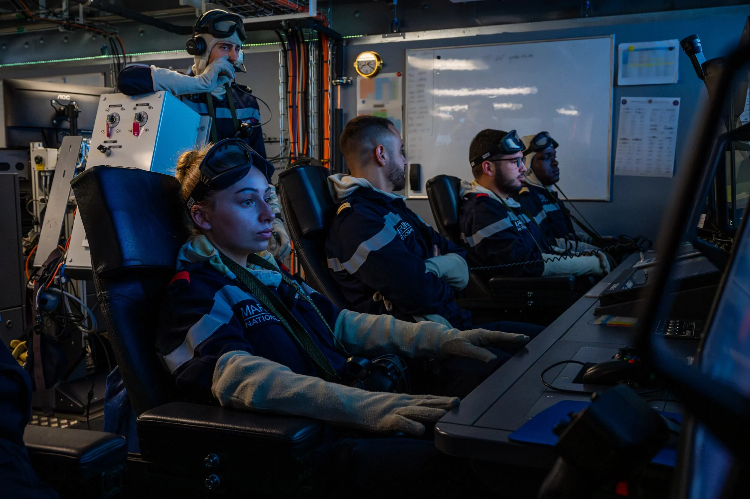 Une équipe de techniciens de conduite et maintenance nucléaire de la marine nationale, au poste de contrôle vérifiant le bon fonctionnement des systèmes