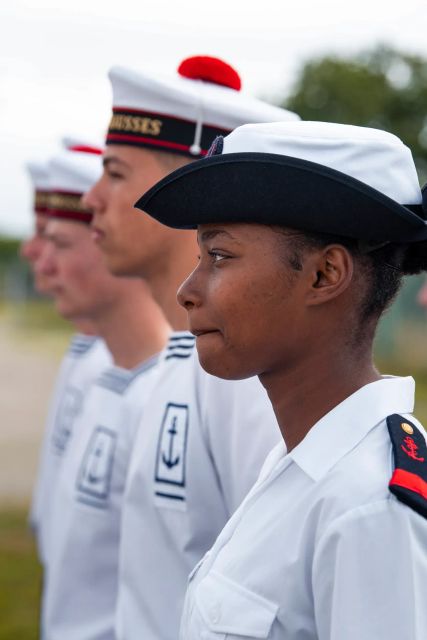 Des matelots de la marine nationale, en uniforme blanc marinière et chemisette, en rang.