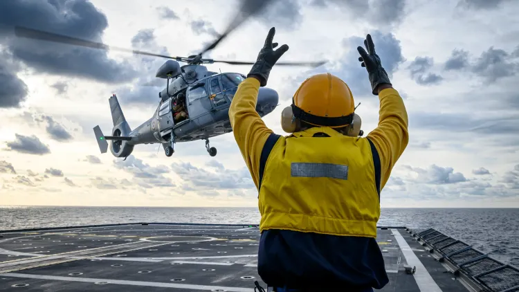 Hélicoptère dauphin de la marine en train d'atterrir et un opérateur de pont lui donnant des instructions 