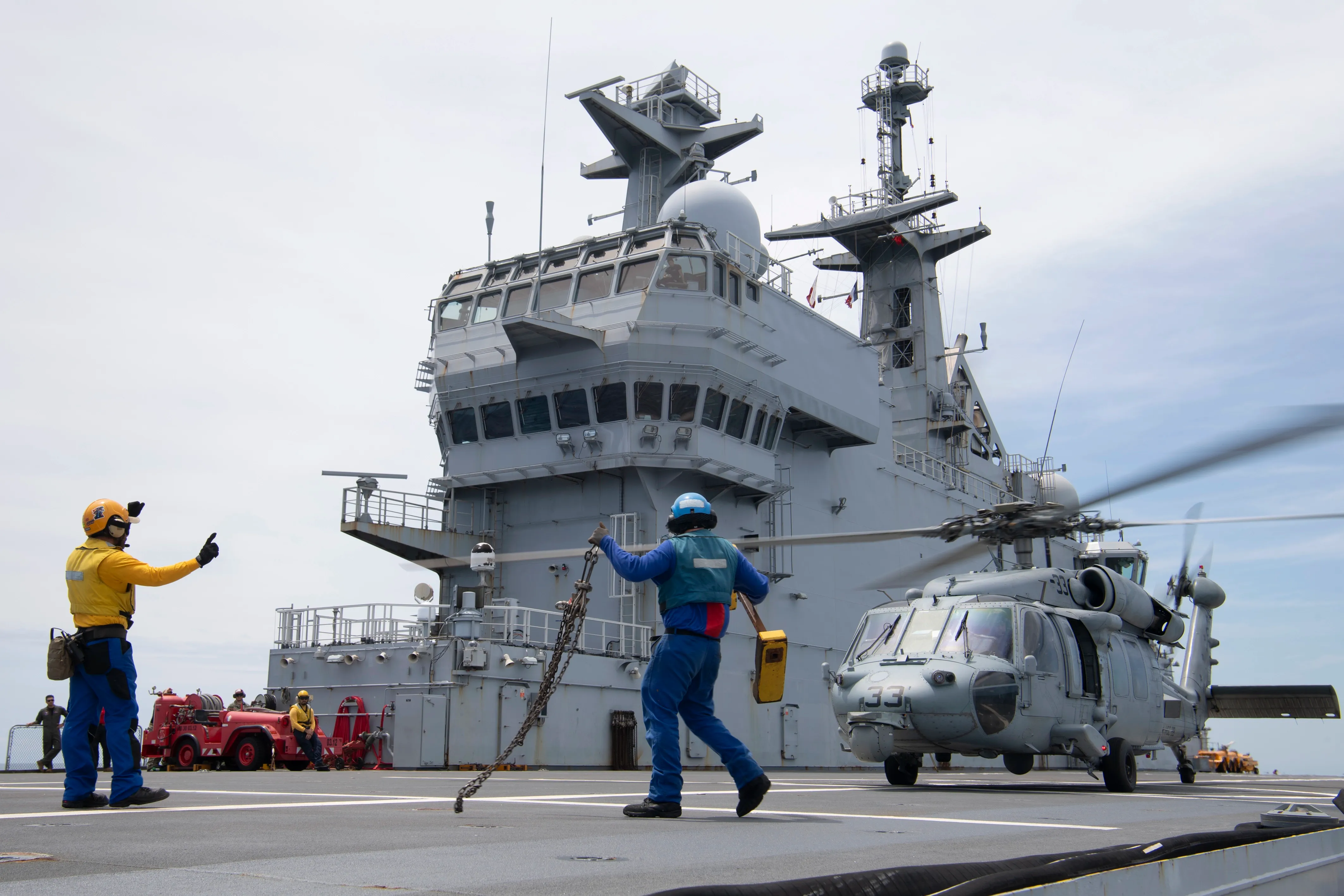Deux opérateurs de manutention des aéronefs au travail sur le pont d'un bâtiment de la Marine Nationale