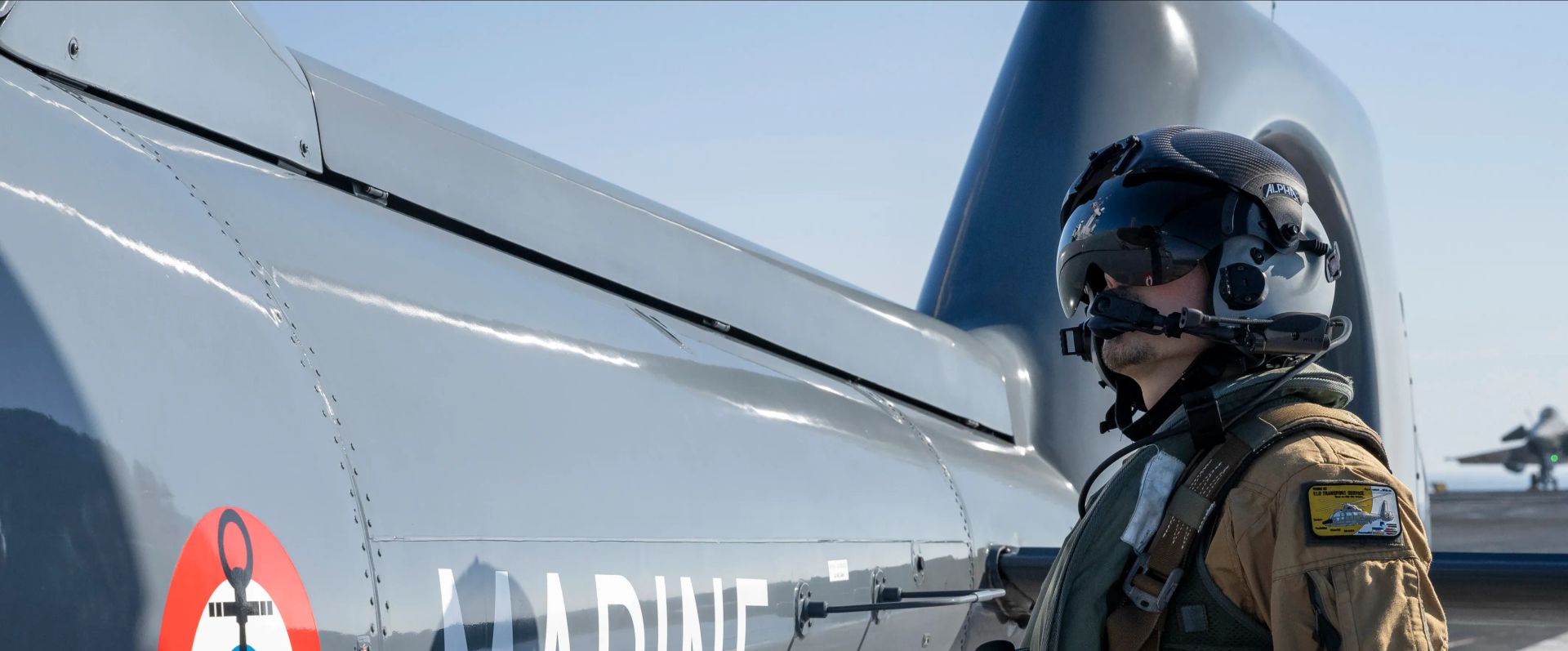 Un personnel naviguant tactique fait face à un hélicoptère de la Marine Nationale