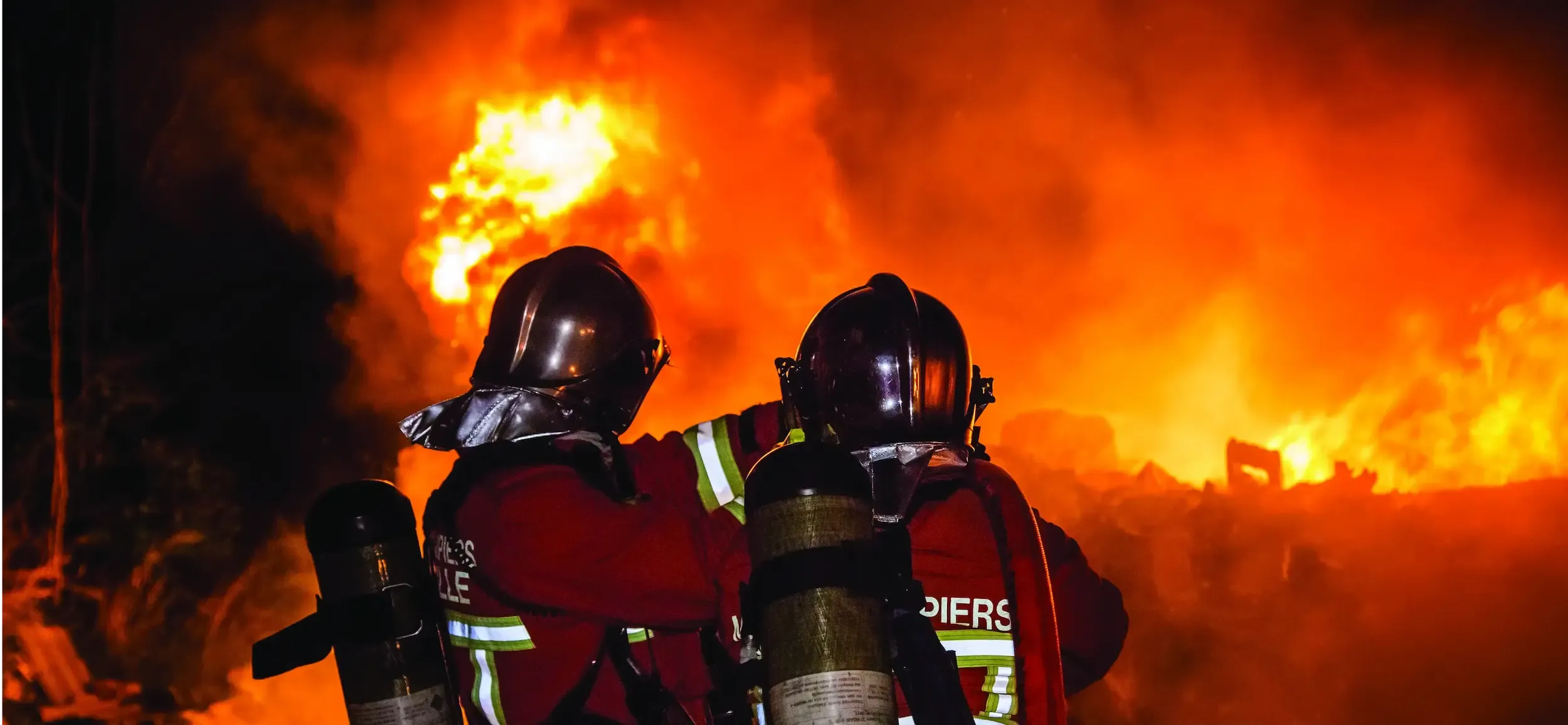Des marins pompiers en train de combattre un incendie ravageur avec de grandes flammes.