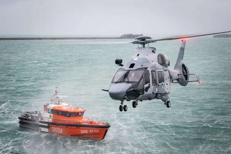 Hélicoptère H160 en pleine mission au-dessus de la mer avec un navire rouge de la SNSM