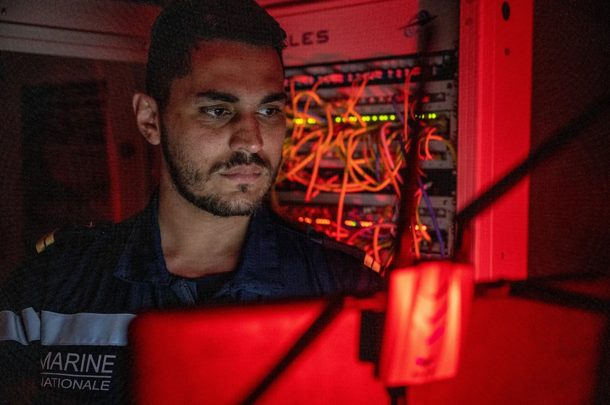 un technicien réseaux et télécommunication travaillant dans un local réseau d'un navire.