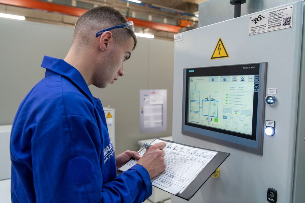 Elève de l'école des apprentis de la marine prenant des notes sur une machine