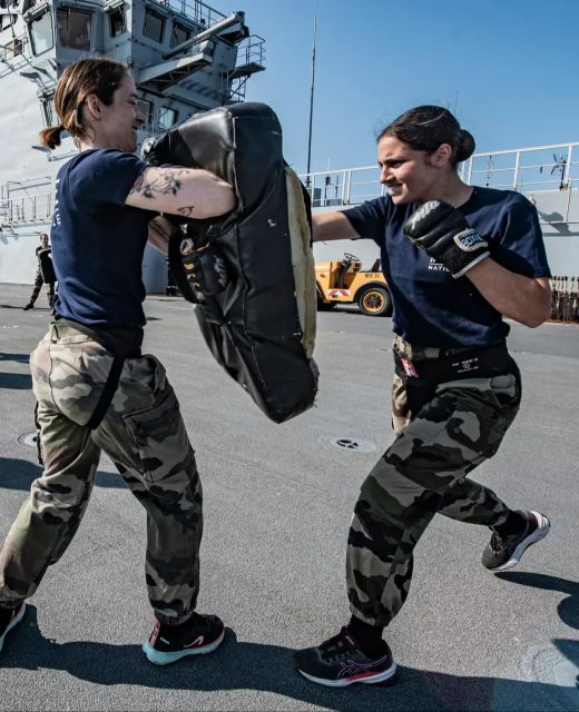 Deux femmes de la Marine nationale s'entrainant à la boxe sur le pont d'un navire.