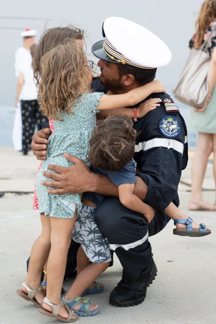 Retrouvailles sur le quai du port, d'un marin et de ses enfants, le marin est encore en uniforme de travail.