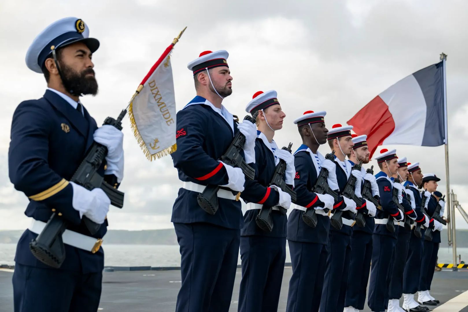 Des marins en rang, avec armes de cérémonies et drapeaux français.