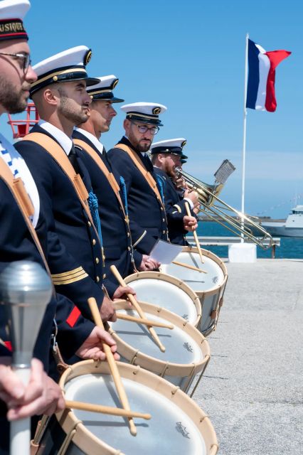 Des musiciens de la marine nationale en uniforme bleu, équipés de tambours, en rang pour la cérémonie de la libération de cherbourg.